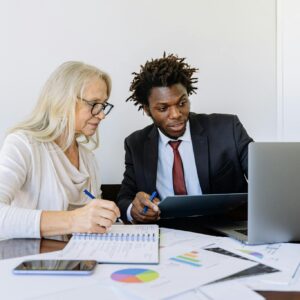 Elderly Woman Looking at the Computer Beside a Man in Black Suit